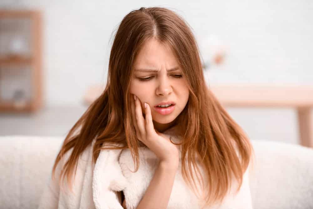 Young woman suffering from toothache at home