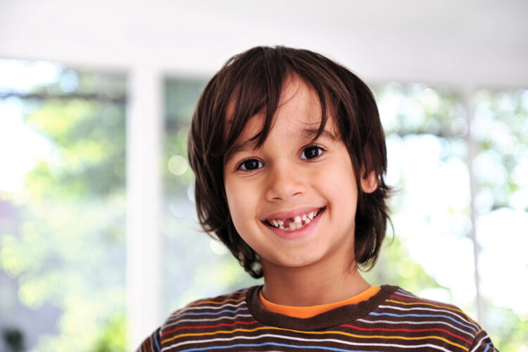 A kid smiling in a camera with his incomplete teeth
